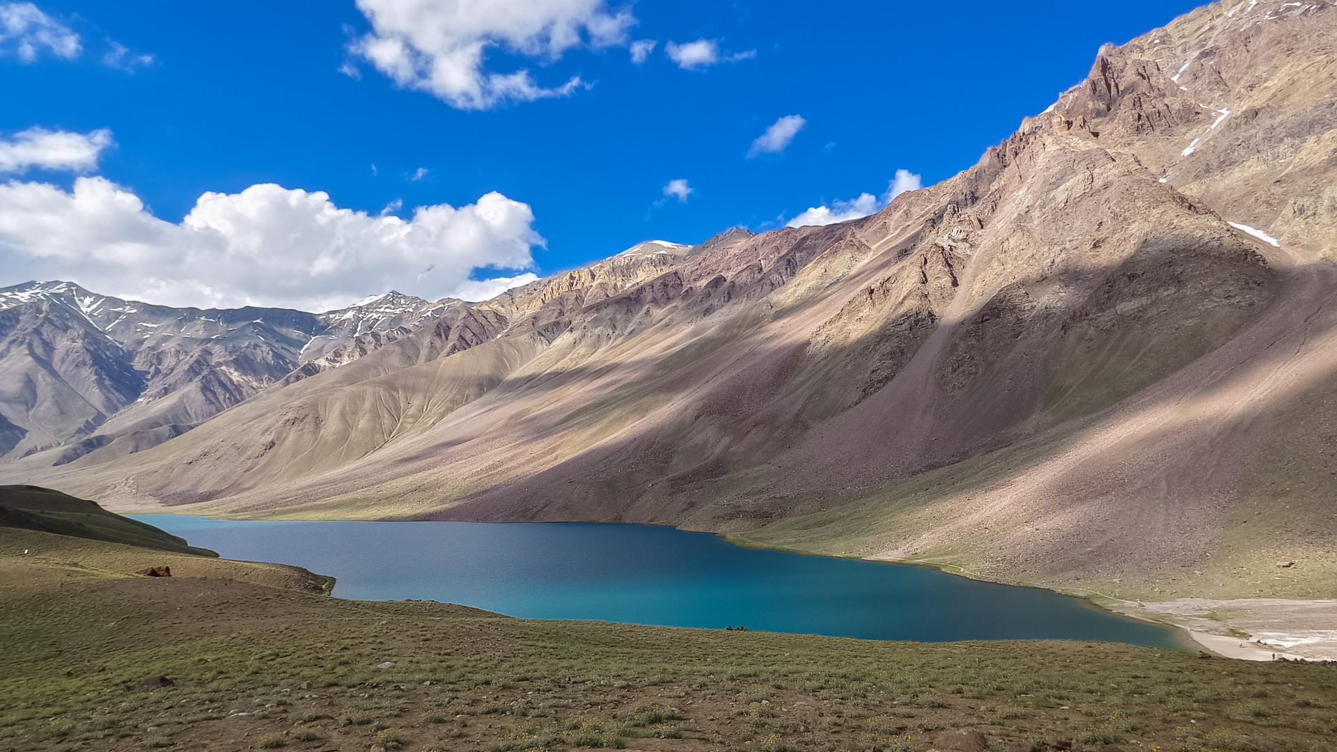 Chandratal Lake in Lahaul-Spiti, a high-altitude lake surrounded by rugged Himalayan mountains under a clear sky.