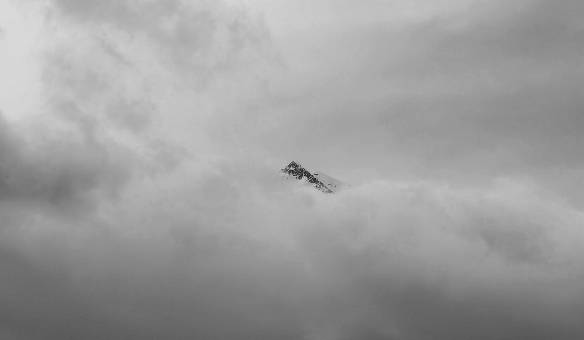 A snow peak visible from a gap between the clouds