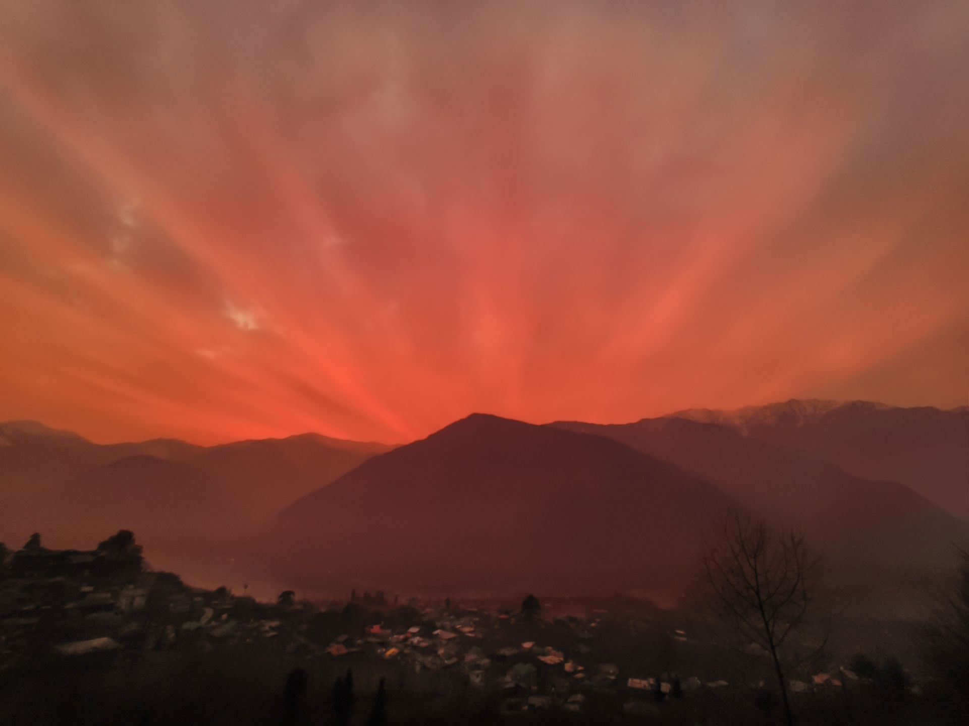 A deep orange sunset sky with warm light spreading across the horizon, photographed in the mountains.