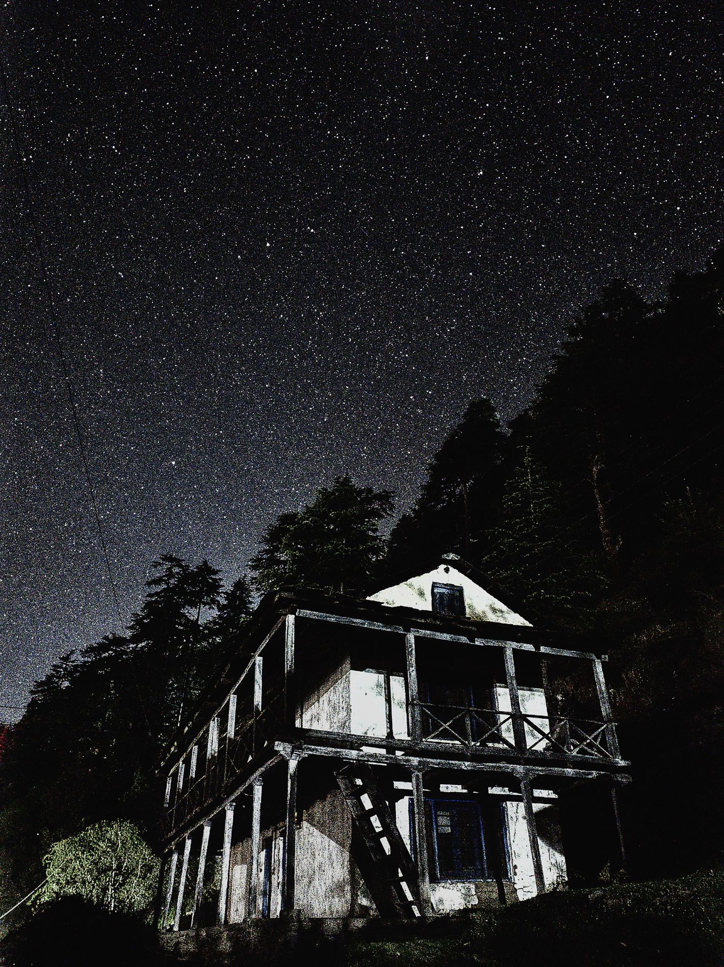 An old Himachali building under a star lit night sky